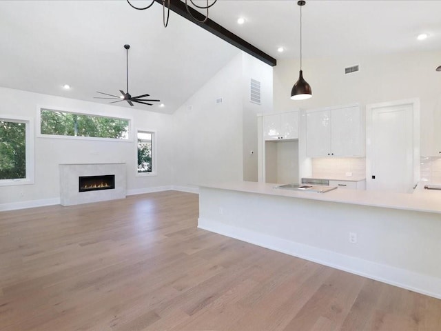 kitchen featuring white cabinetry, high vaulted ceiling, light wood-type flooring, pendant lighting, and beam ceiling