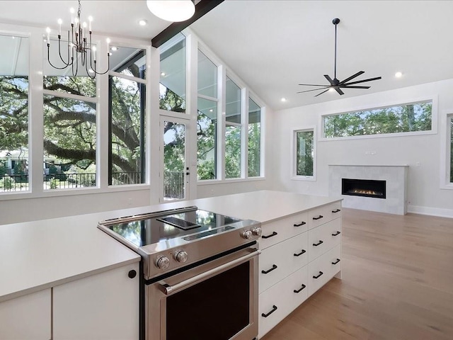 kitchen with a warm lit fireplace, electric range, white cabinetry, and light countertops