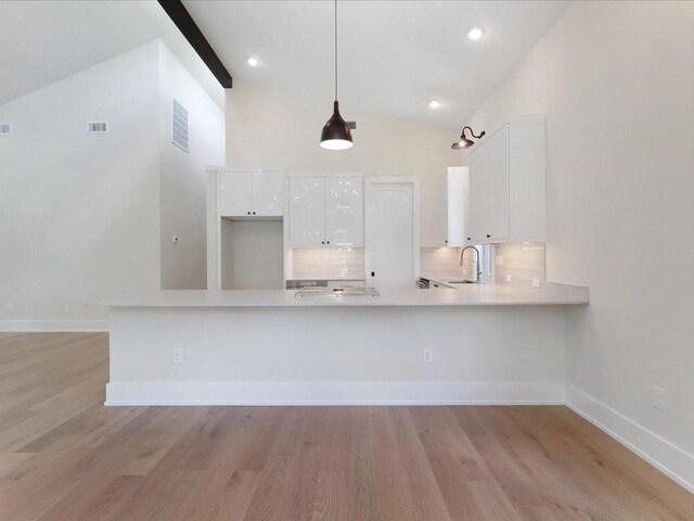 kitchen with decorative light fixtures, sink, white cabinets, backsplash, and kitchen peninsula