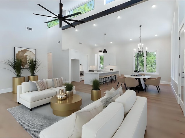 living area featuring light wood finished floors, a towering ceiling, and a healthy amount of sunlight