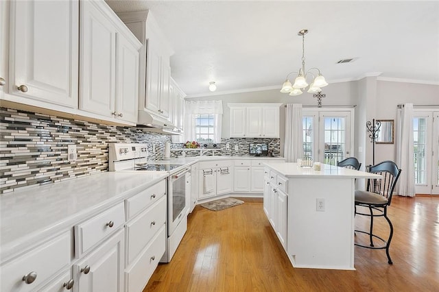 kitchen with white electric range oven, a breakfast bar area, a kitchen island, and white cabinets