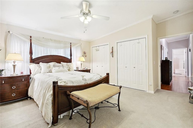 bedroom with light carpet, ceiling fan, vaulted ceiling, crown molding, and two closets