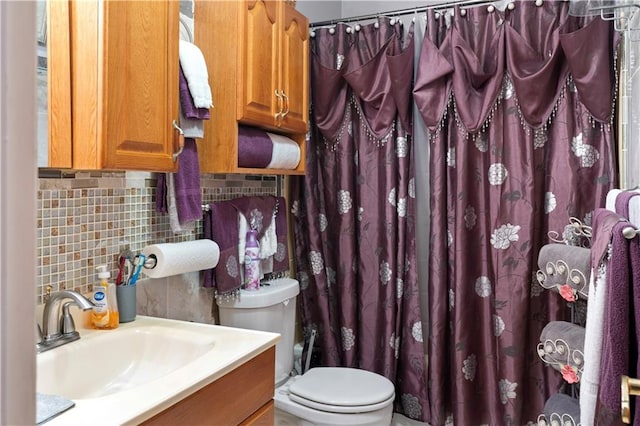 bathroom with walk in shower, vanity, toilet, and tasteful backsplash