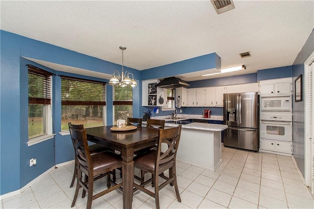 tiled dining area featuring sink, a notable chandelier, and a textured ceiling