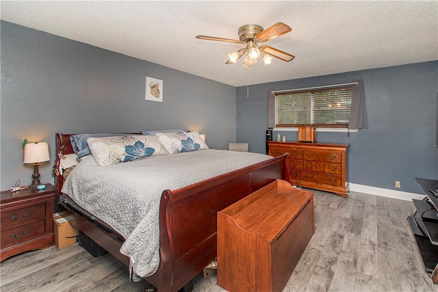 bedroom featuring light hardwood / wood-style flooring, a textured ceiling, and ceiling fan