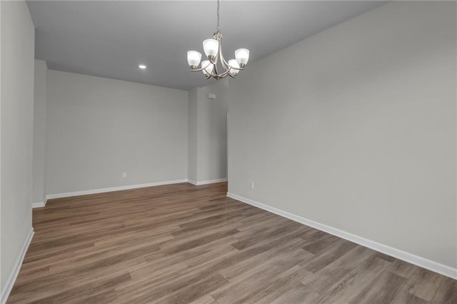 spare room featuring wood-type flooring and a chandelier