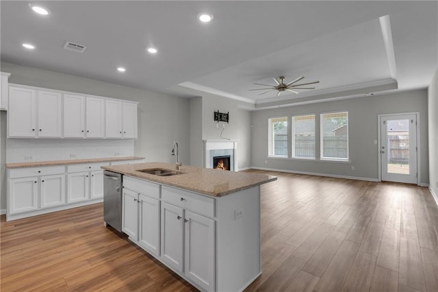 kitchen featuring white cabinets, stainless steel dishwasher, plenty of natural light, and an island with sink