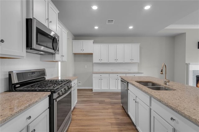 kitchen with sink, white cabinets, stainless steel appliances, and light wood-type flooring