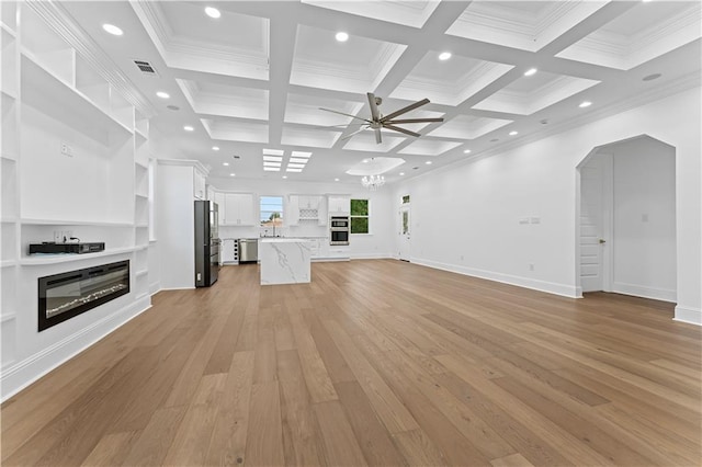 unfurnished living room with ceiling fan with notable chandelier, light hardwood / wood-style floors, coffered ceiling, beam ceiling, and ornamental molding