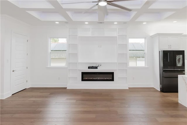 unfurnished living room with beam ceiling, coffered ceiling, and light wood-type flooring