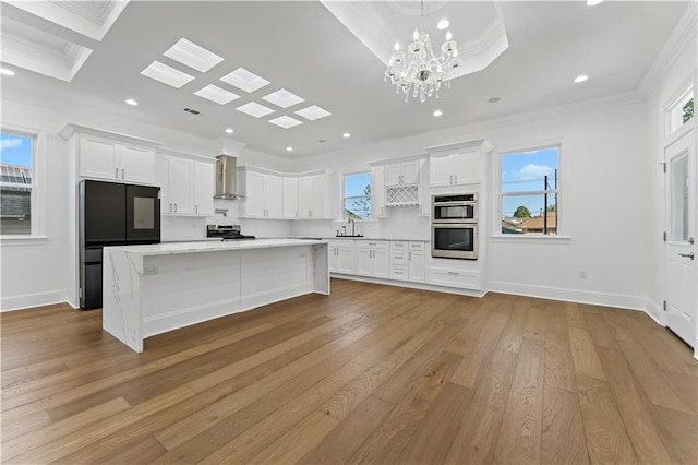 kitchen with wall chimney exhaust hood, white cabinets, and light wood-type flooring