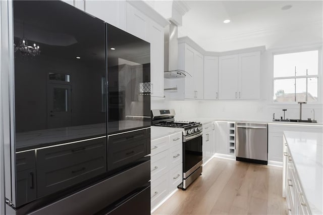 kitchen with sink, white cabinetry, stainless steel appliances, wall chimney exhaust hood, and light hardwood / wood-style flooring