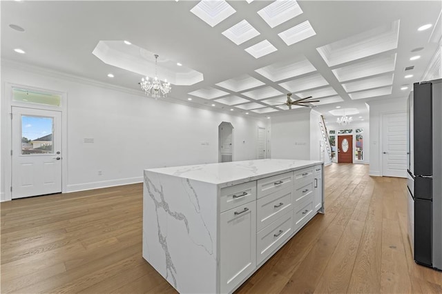 kitchen with a kitchen island, light stone countertops, pendant lighting, light wood-type flooring, and white cabinets