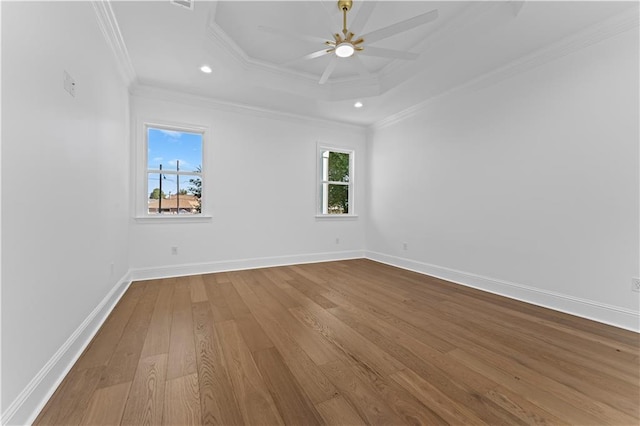 empty room with crown molding, hardwood / wood-style flooring, a tray ceiling, and ceiling fan