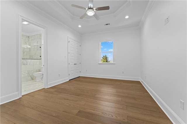 unfurnished bedroom with hardwood / wood-style floors, crown molding, and ensuite bath