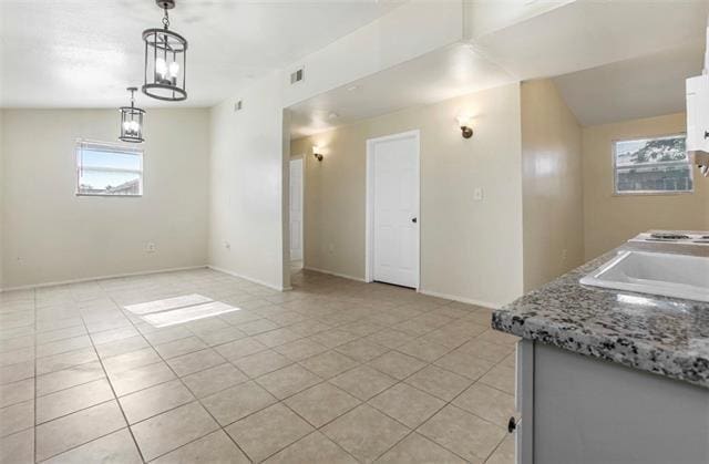 kitchen featuring white cabinetry, light tile patterned flooring, lofted ceiling, and hanging light fixtures