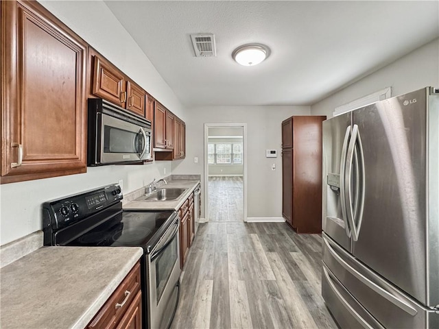 kitchen featuring appliances with stainless steel finishes, sink, and light hardwood / wood-style floors