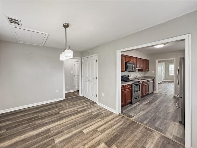 kitchen featuring stainless steel appliances, dark hardwood / wood-style floors, sink, and decorative light fixtures