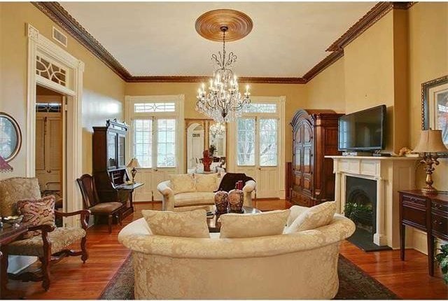 living room featuring ornamental molding, dark wood-type flooring, and an inviting chandelier