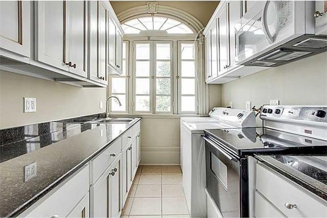 laundry room featuring separate washer and dryer, sink, and light tile patterned flooring