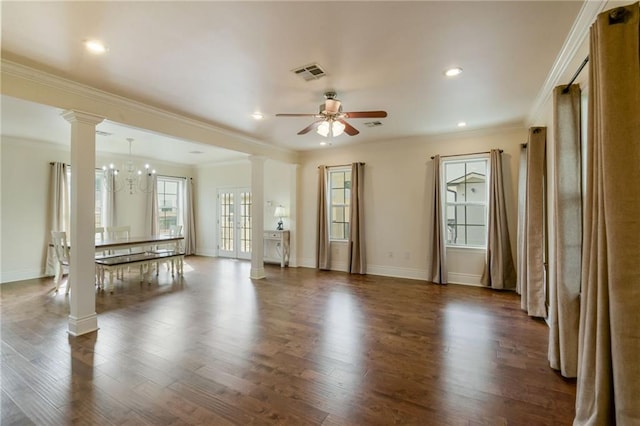 unfurnished living room featuring ornamental molding, ornate columns, dark hardwood / wood-style floors, and ceiling fan with notable chandelier