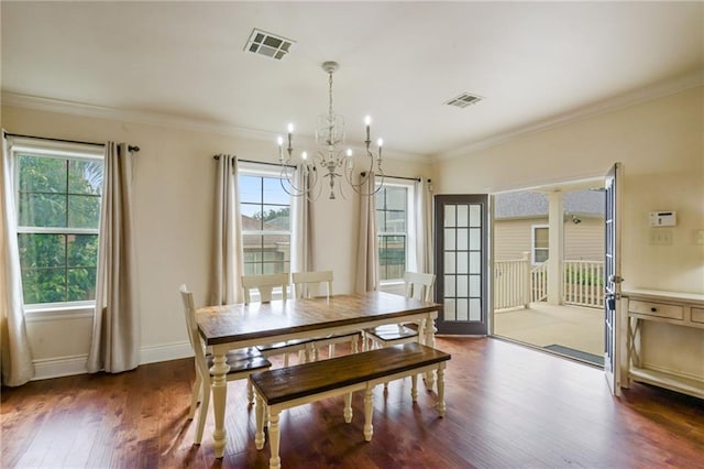 dining space featuring dark wood-type flooring, a notable chandelier, crown molding, and plenty of natural light