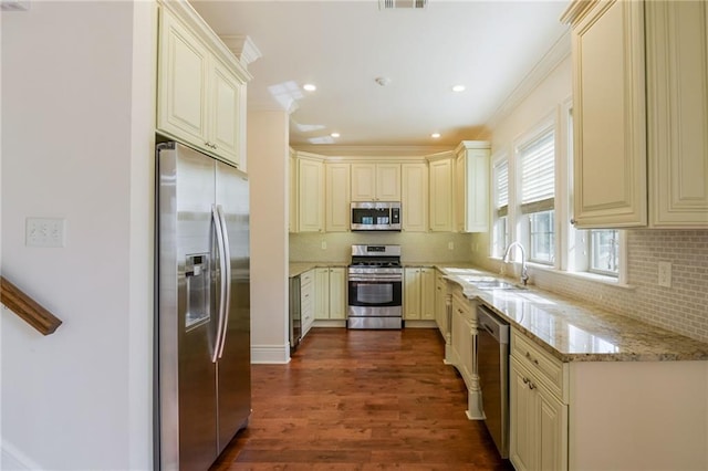 kitchen featuring cream cabinets, stainless steel appliances, sink, light stone counters, and dark hardwood / wood-style flooring