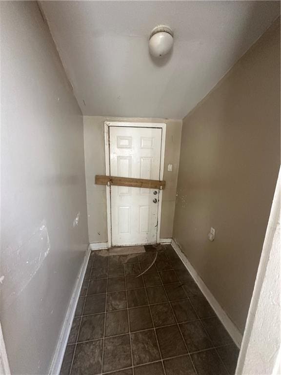 entryway with lofted ceiling and dark tile patterned floors