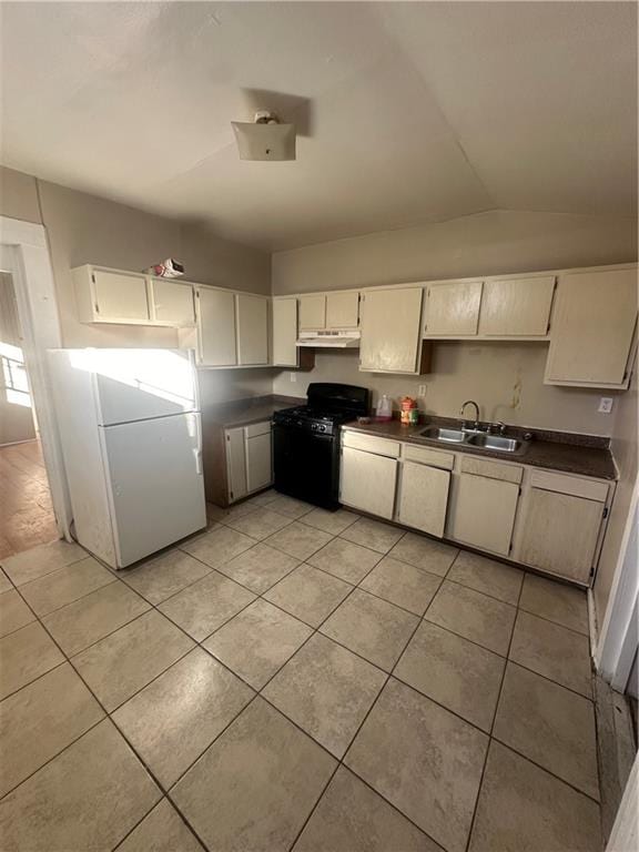 kitchen featuring gas stove, lofted ceiling, light tile patterned floors, white fridge, and sink