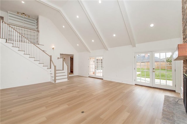 unfurnished living room with a fireplace, french doors, beamed ceiling, high vaulted ceiling, and light hardwood / wood-style flooring