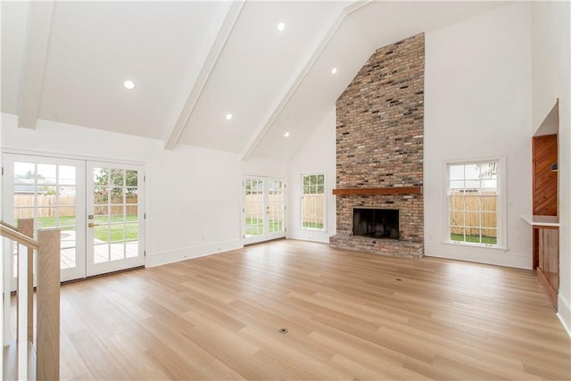 unfurnished living room with a brick fireplace, high vaulted ceiling, and plenty of natural light