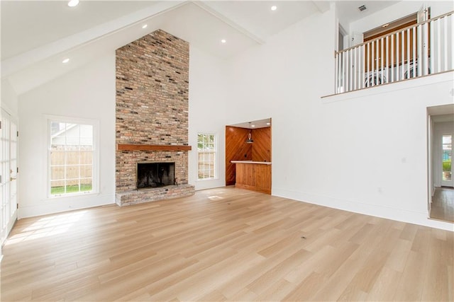 unfurnished living room featuring beamed ceiling, a brick fireplace, light wood-type flooring, and high vaulted ceiling