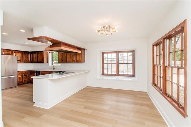 kitchen featuring black electric stovetop, light hardwood / wood-style flooring, stainless steel fridge, and a healthy amount of sunlight