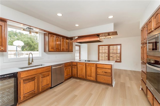 kitchen featuring sink, appliances with stainless steel finishes, kitchen peninsula, and light hardwood / wood-style floors