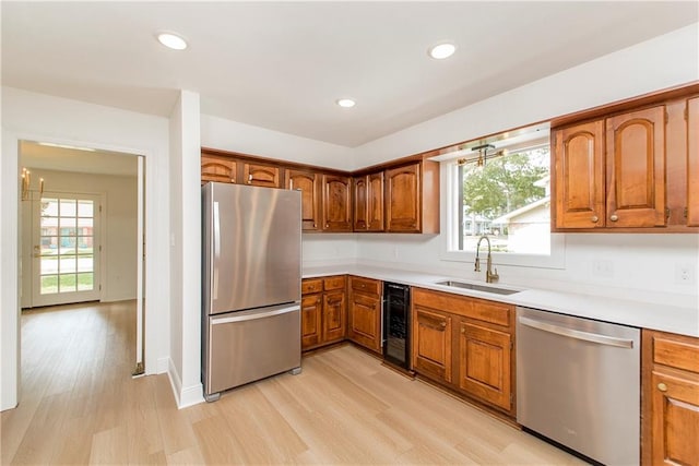 kitchen featuring wine cooler, sink, appliances with stainless steel finishes, and light wood-type flooring