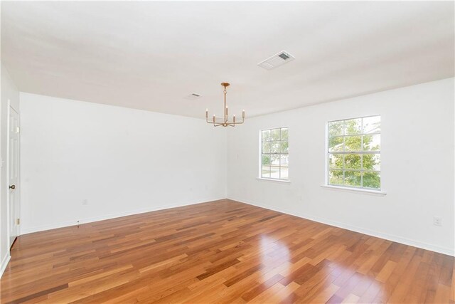 spare room with light hardwood / wood-style flooring and a chandelier