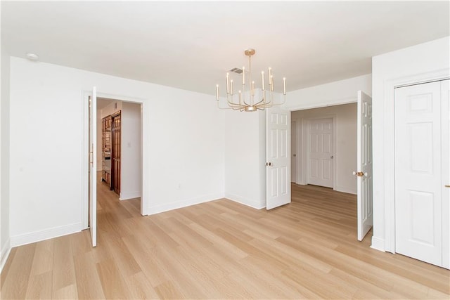 empty room featuring a chandelier and light hardwood / wood-style flooring