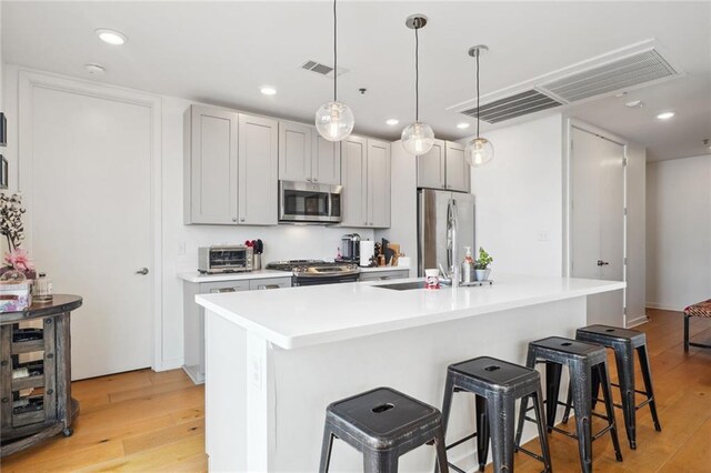 kitchen featuring a kitchen breakfast bar, a center island with sink, light hardwood / wood-style flooring, and appliances with stainless steel finishes