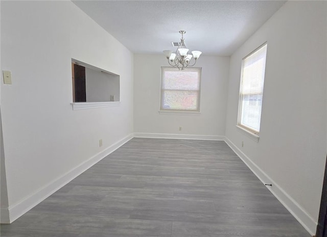 spare room with dark hardwood / wood-style flooring and an inviting chandelier