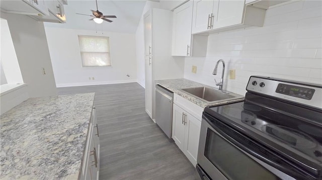 kitchen with dark hardwood / wood-style flooring, light stone counters, stainless steel appliances, sink, and white cabinetry