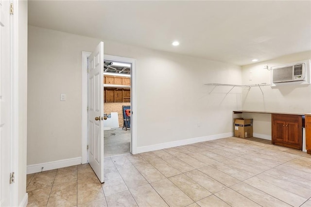 basement featuring light tile patterned floors and a wall unit AC