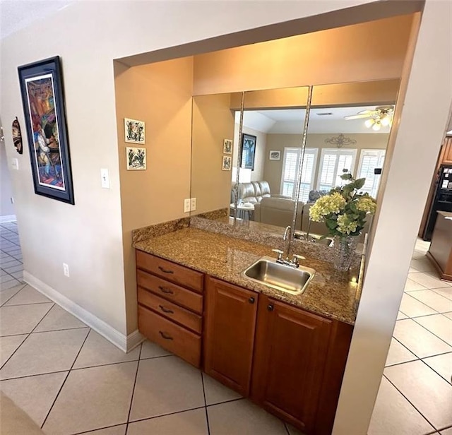 kitchen featuring light tile patterned floors, ceiling fan, sink, and light stone counters