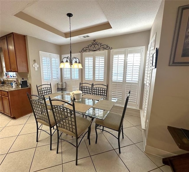 tiled dining room with a textured ceiling, an inviting chandelier, and a raised ceiling