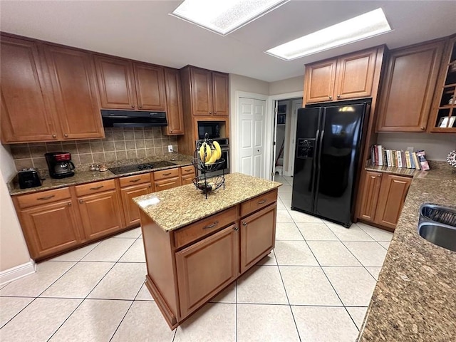 kitchen with light stone counters, black appliances, light tile patterned floors, ventilation hood, and backsplash