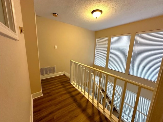 hallway featuring dark wood-type flooring and a textured ceiling