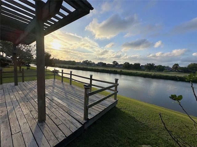 view of dock featuring a deck with water view and a lawn