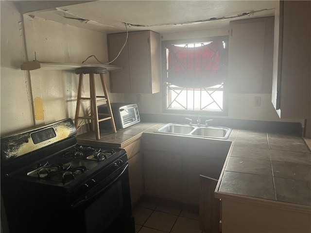 kitchen featuring tile counters, sink, tile patterned floors, and black gas range oven