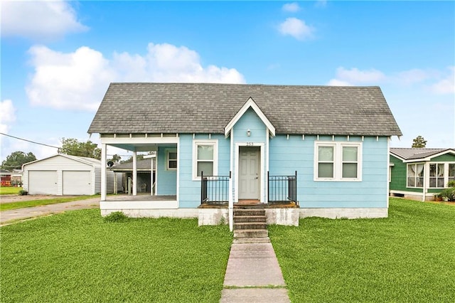 bungalow-style house featuring a garage, a front lawn, an outdoor structure, and a porch