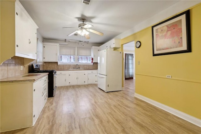 253 Central Ave, Reserve, LA 70084 - kitchen with stainless steel gas range, freestanding refrigerator, ceiling fan, tasteful backsplash, and white cabinets