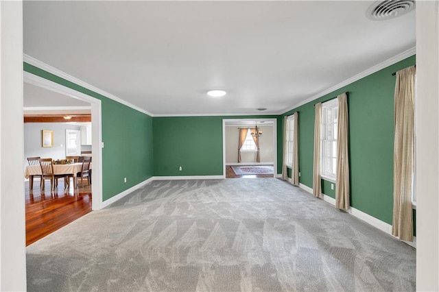 carpeted spare room featuring baseboards, visible vents, and ornamental molding